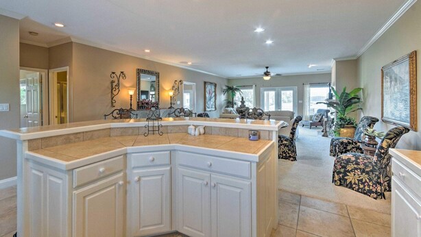 A spacious kitchen with a large island, white cabinetry, and a dining area with floral-patterned chairs. - Lakeview Condo w/ Balcony+Pool Access, Sunrise View! (Lake Hamilton)