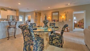 A dining area with a glass table surrounded by floral-patterned chairs, a decorative vase, and a mirror on the wall. - Lakeview Condo w/ Balcony+Pool Access, Sunrise View! (Lake Hamilton)