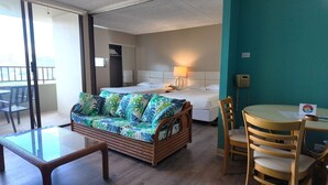 A room with a bed, a sofa, a dining table, and chairs.
