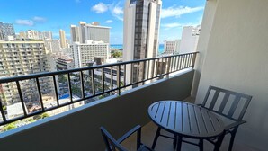 Un balcón con mesa y sillas, con vistas a un paisaje urbano de edificios altos.