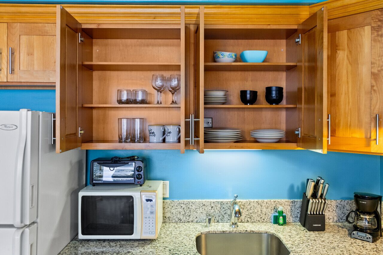 A compact kitchen with wooden cabinets, a microwave, a toaster, and a coffee maker.