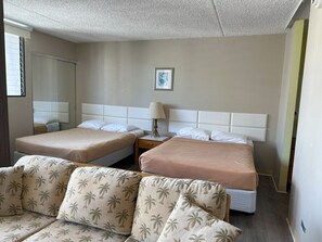 Une chambre d’hôtel avec deux lits, un canapé, une table de chevet avec une lampe et un tableau encadré au mur.