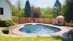 Un patio trasero con piscina, cerca de madera y una casa.