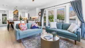 A spacious living room with two light blue sofas, a coffee table, and a ceiling fan. - Paradise Cove with Mountain-Views Pool & Spa  (La Quinta)