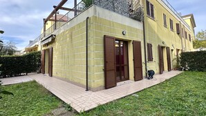 Ein zweistöckiges Gebäude mit Balkon, einer Tür mit Fenster und einem Schlauch auf dem Boden.