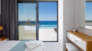 A hotel room with a bed, a bedside table, a bathroom with a mirror, and a view of the ocean through a sliding door. - Brand new villa in Falasarna★Seaview★Infinity pool (Phalasarna)