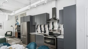 A modern kitchen with grey cabinets, stainless steel appliances, and a dining area with blue chairs and a table set for four.
