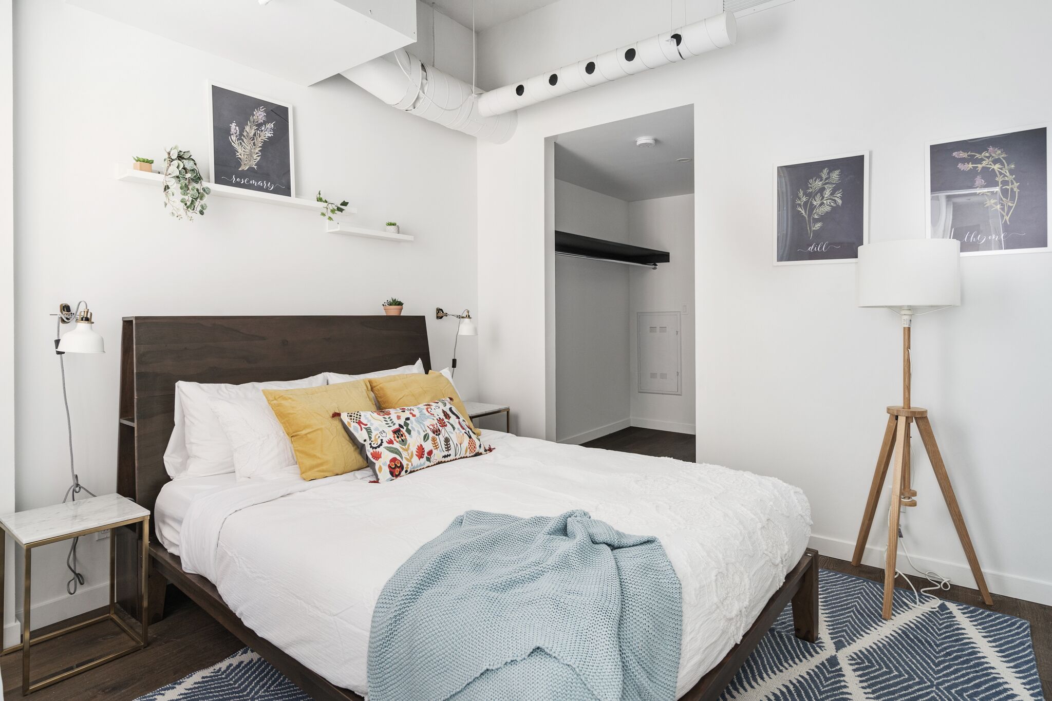 Une chambre moderne avec un grand lit, des tables de chevet, une lampe sur pied et des œuvres d’art décoratives au mur.