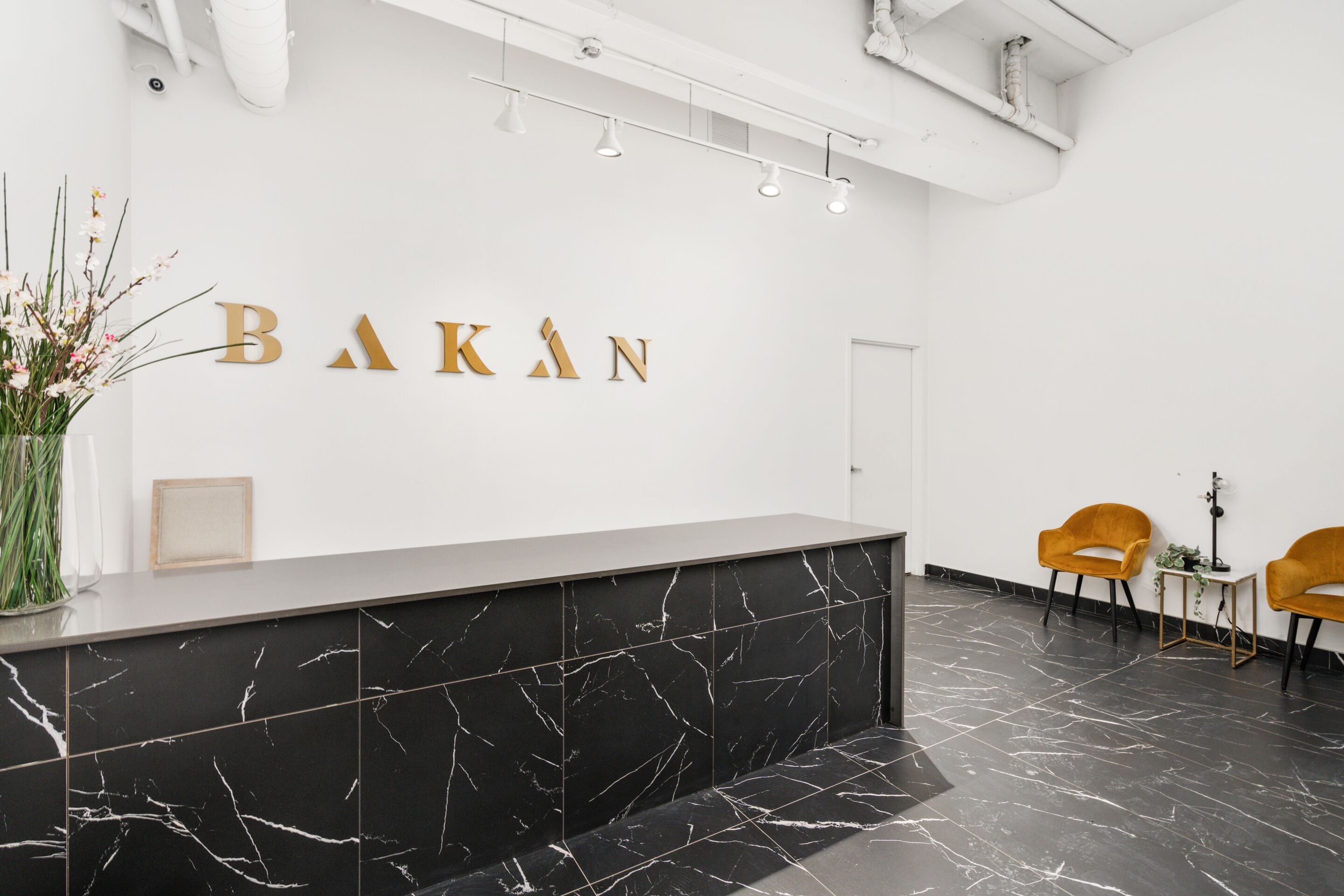 En receptionsdisk med en marmorskiva och en väggmonterad skylt med texten ”BAKAN”.