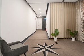 A hallway with a star-patterned carpet, a reception desk, and potted plants. - Bakan - Sainte Catherine (Montreal)