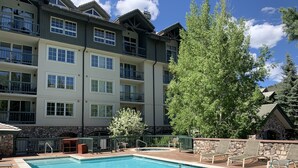 A hotel with a swimming pool, outdoor seating, and a stone facade. - Beaver Creek Ski-in/Ski-out Condo (Avon)