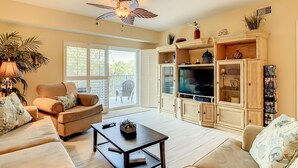 A living room with a sofa, a coffee table, a TV, and a ceiling fan.