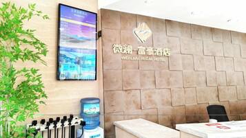 A reception desk with a digital display, a water dispenser, and a sign for the Weilian Regal Hotel.