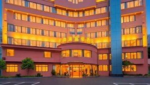 A multi-story hotel with a curved facade, illuminated windows, and a central entrance. - Yizhang Fuhao Hotel (Yizhang)