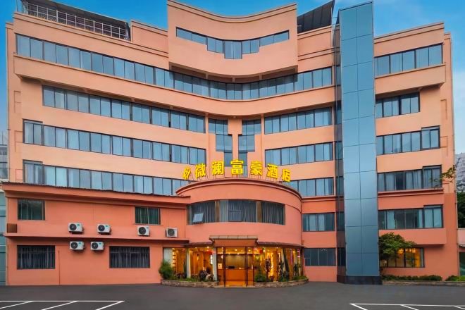 Un hotel de varios pisos con fachada curva, ventanas amplias y una entrada destacada con señalización.