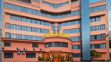 Un hotel de varios pisos con fachada curva, ventanas amplias y una entrada destacada con señalización.