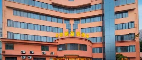 Un hotel de varios pisos con fachada curva, ventanas amplias y una entrada destacada con señalización.