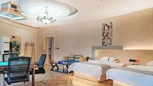 A hotel room with a herringbone floor, a desk with a chair, a bed, a bedside table, and a wall-mounted artwork. - Yizhang Fuhao Hotel (Yizhang)