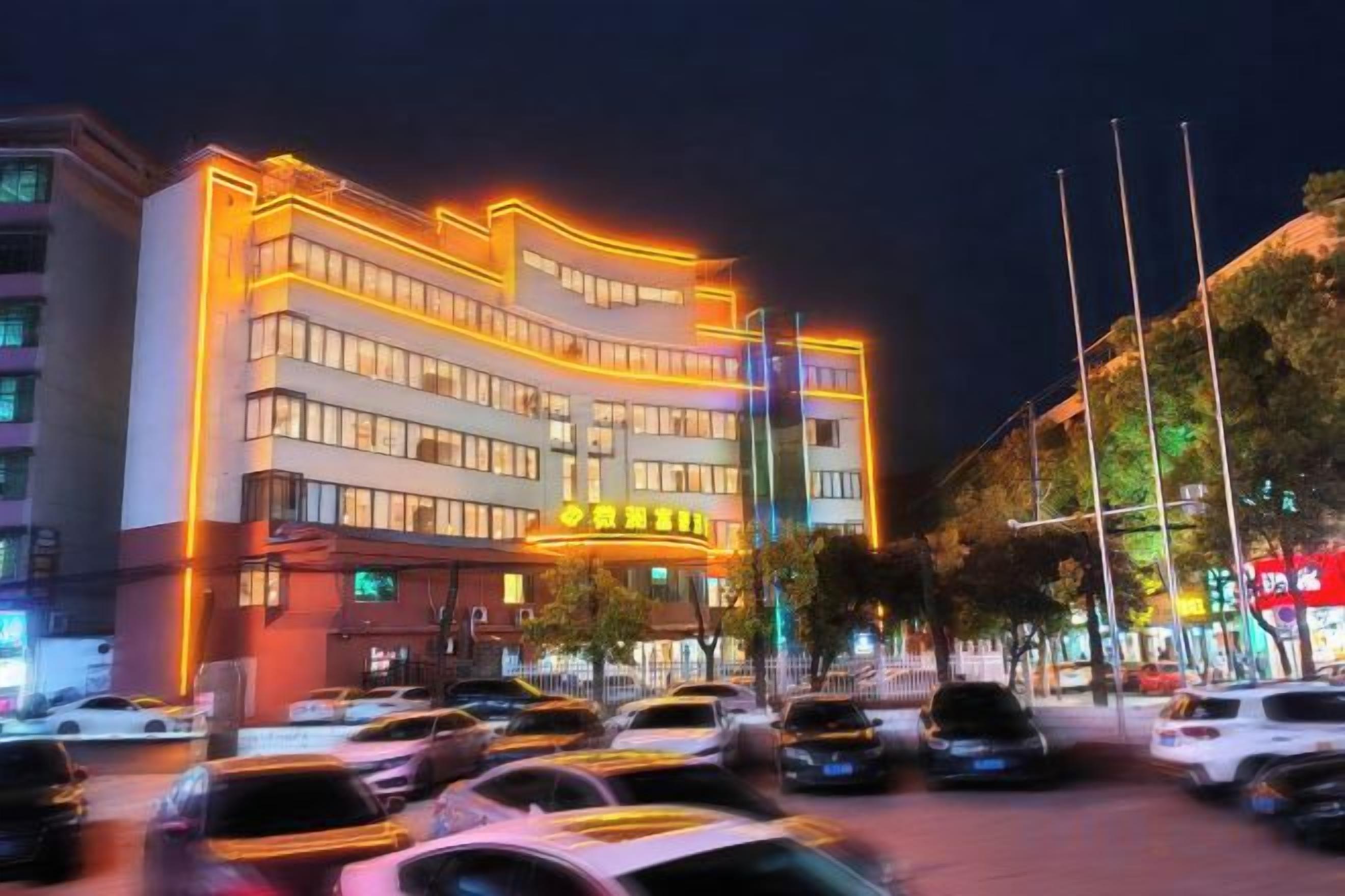 A multi-story hotel with a prominent entrance and a parking lot in front.