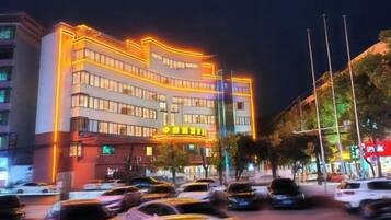 A multi-story hotel with a prominent entrance and a parking lot in front.