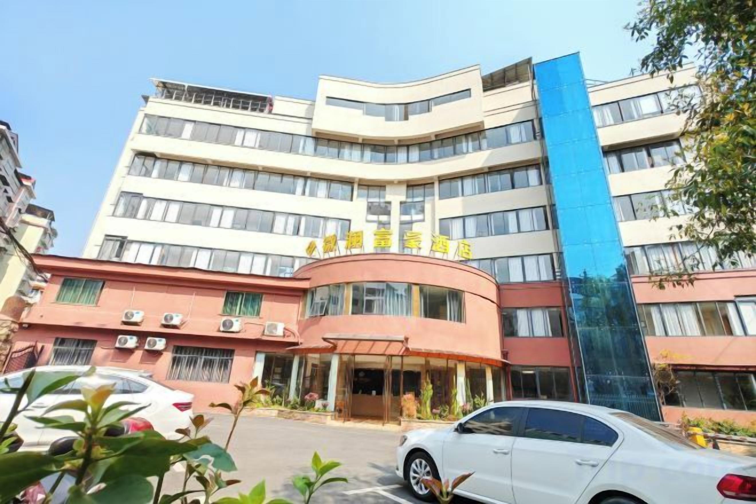 A multi-story hotel with a curved facade, a blue vertical accent, and a clear entrance.