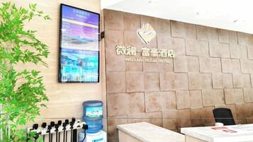 A reception desk with a digital display, a water dispenser, and a sign for the Weilan Regal Hotel.