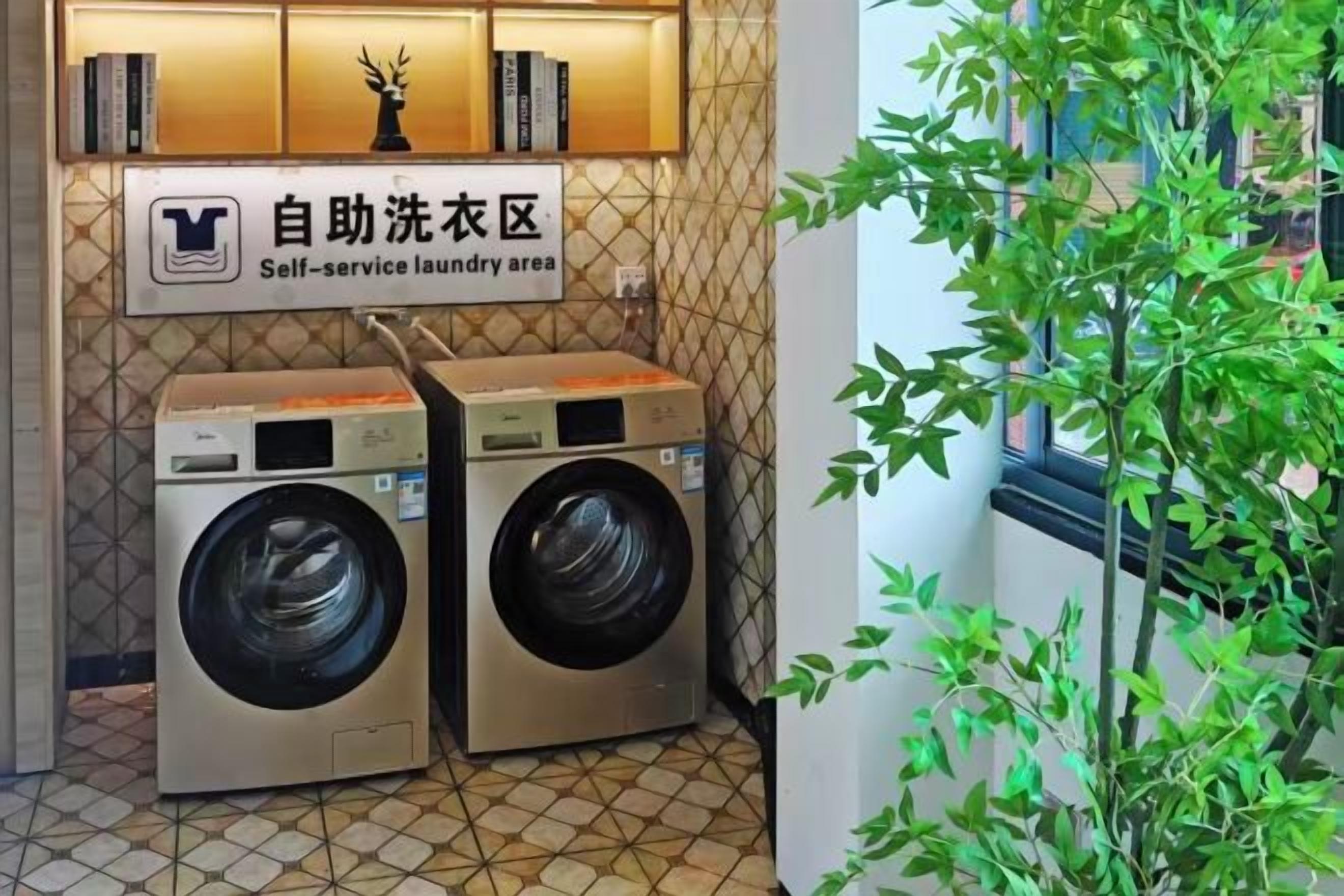 A self-service laundry area with two washing machines and a sign indicating the location.