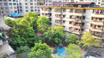 Un edificio residencial de varios pisos con balcones, un patio con árboles y una piscina.