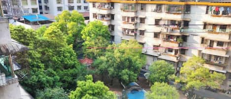 Un edificio residencial de varios pisos con balcones, un patio con árboles y una piscina.