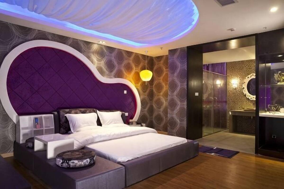A modern bedroom with a large bed, a vanity, and a walk-in closet.