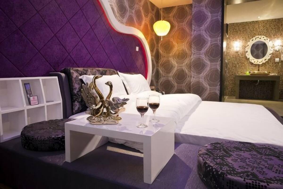 A modern bedroom with a bed, a small table with decorative items, and a nightstand.
