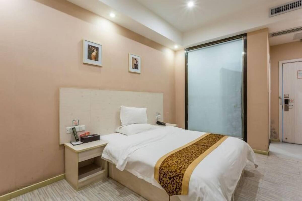 A hotel room with a bed, bedside table, and a sliding door to a bathroom.