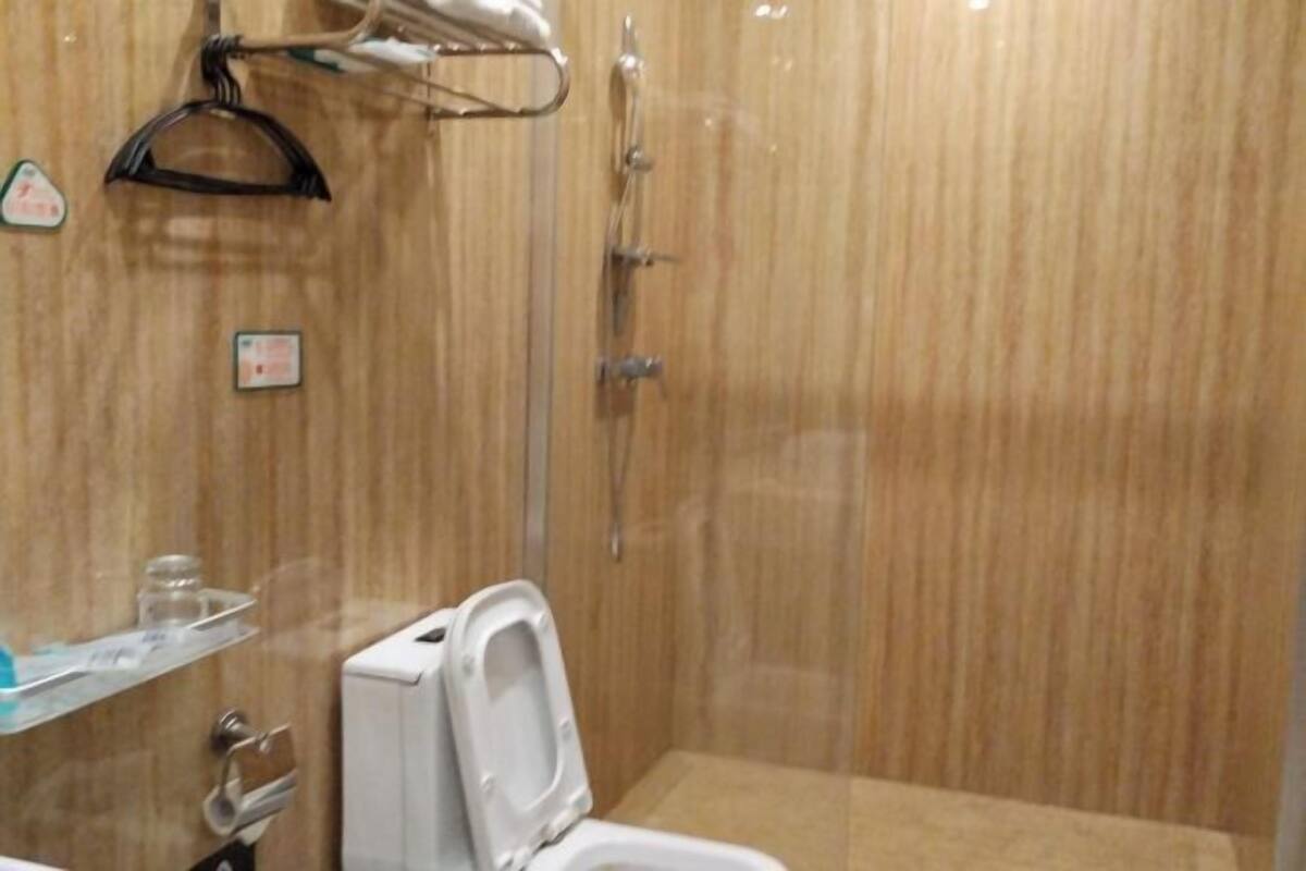 A small, enclosed shower stall with a white toilet and a glass shower door.