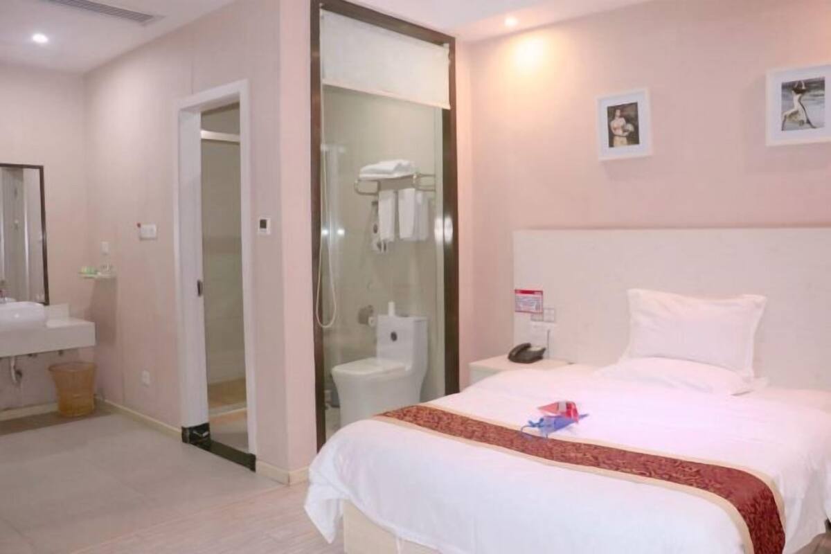 A hotel room with a bed, a bathroom, and a shower area.