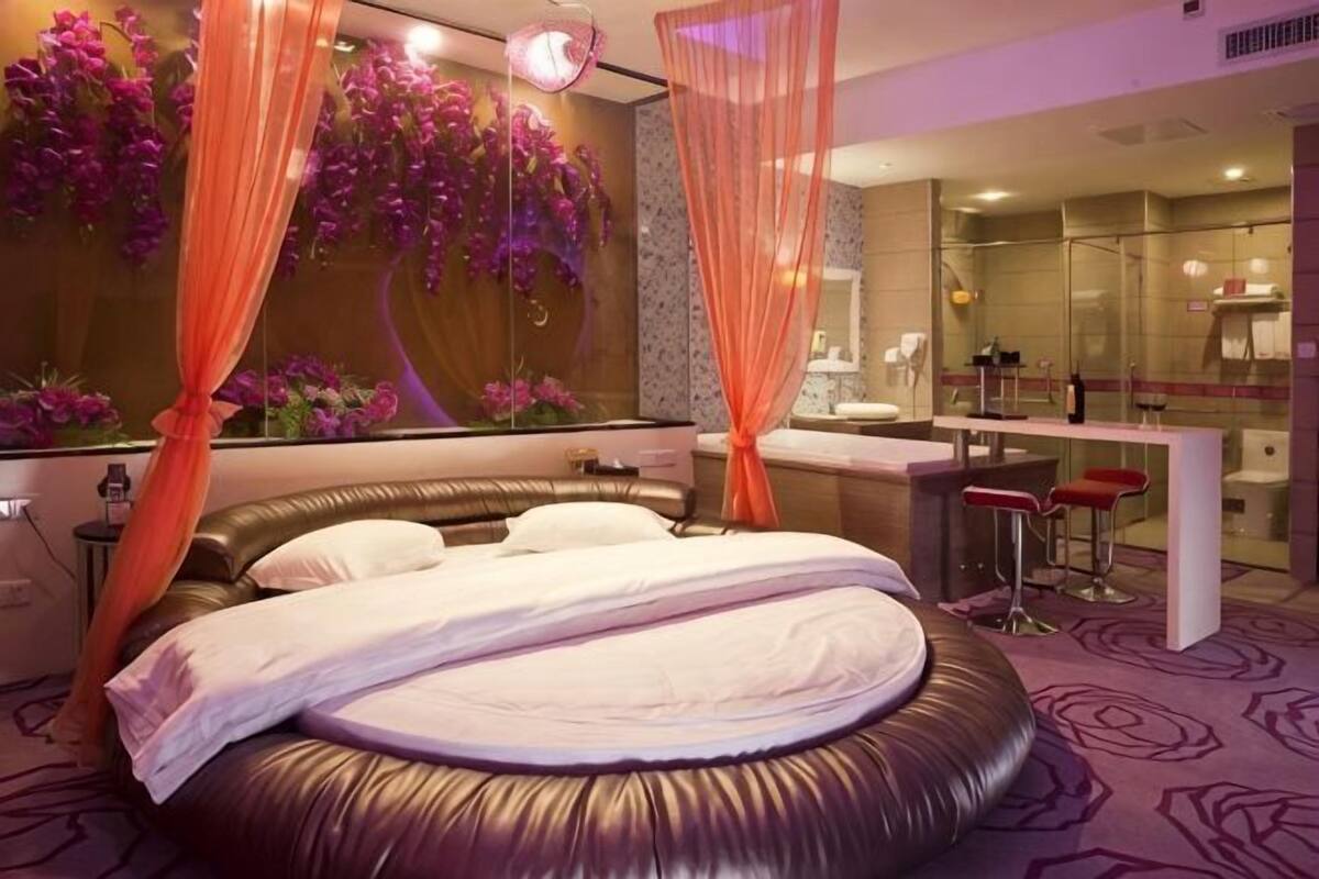 A modern bedroom with a circular bed, a vanity, and a shower area.