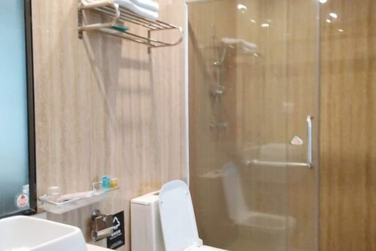 A modern bathroom with a glass shower enclosure, a white sink, and a towel rack.
