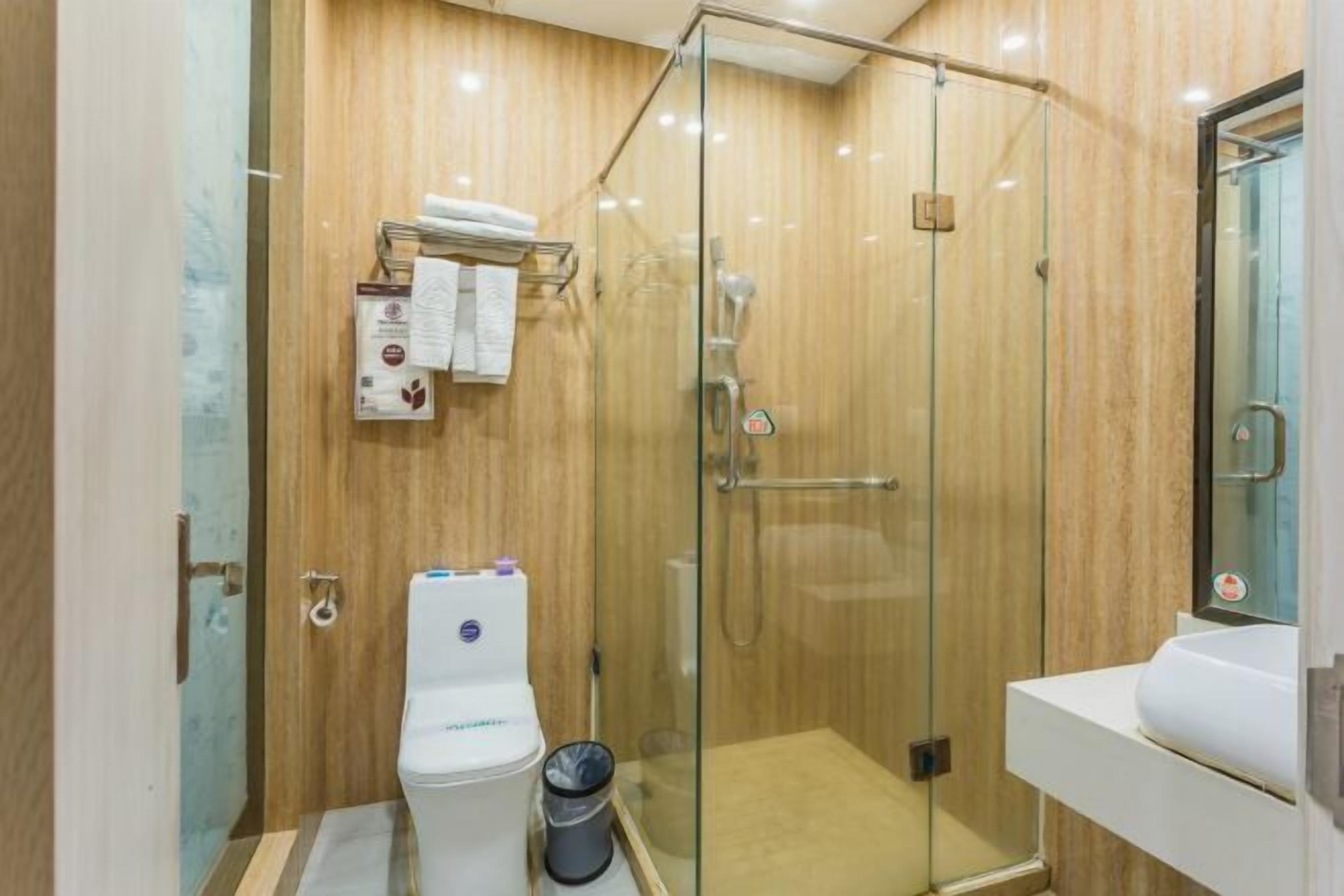 A modern bathroom with a glass-enclosed shower, a toilet, and a sink.