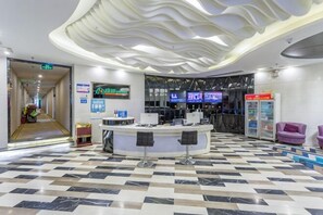 A lobby with a check-in counter, a reception desk, and a digital information board. - Yiyue Express Hotel (Guangzhou)