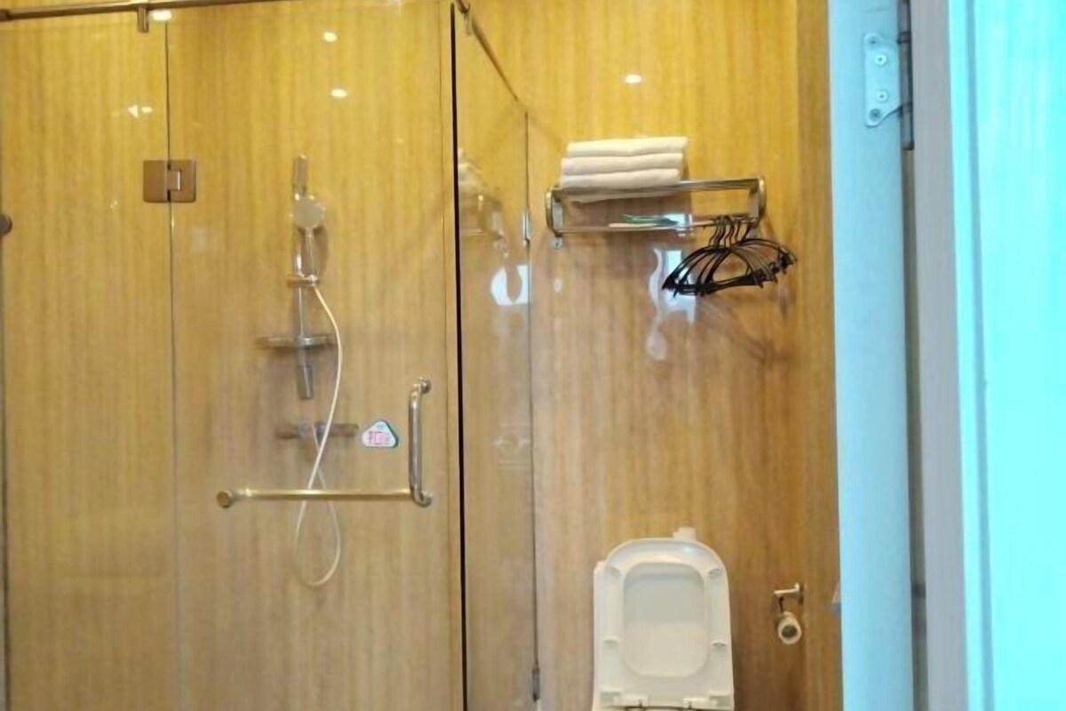 A bathroom with a wooden vanity, a towel rack, a shower, and a toilet.