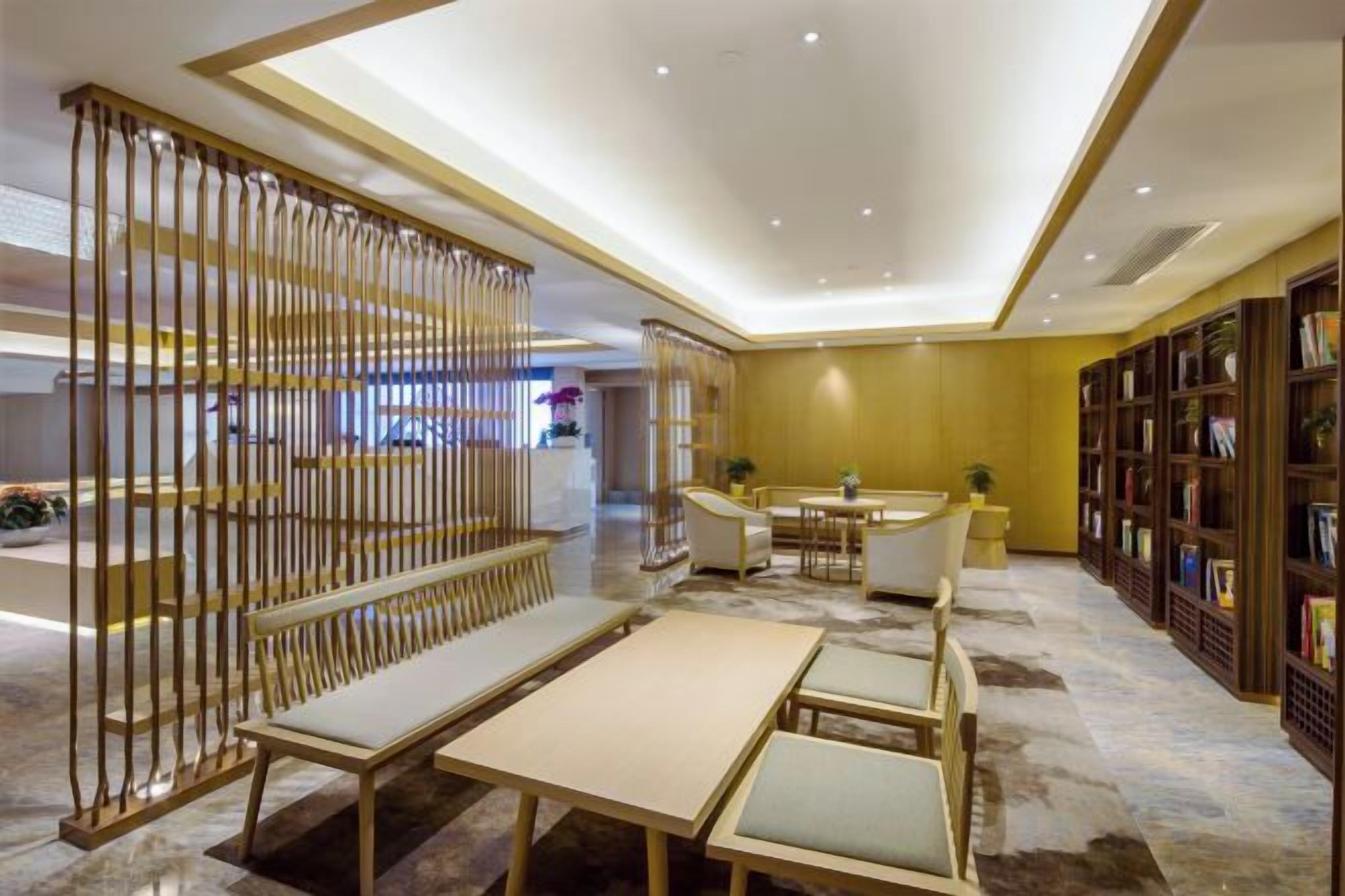 Vestíbulo de hotel con recepción, zona de estar y estanterías.