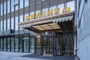 A hotel entrance with a modern design, featuring glass doors and a covered entrance area. - Lindao Holiday Inn (Chengdu)