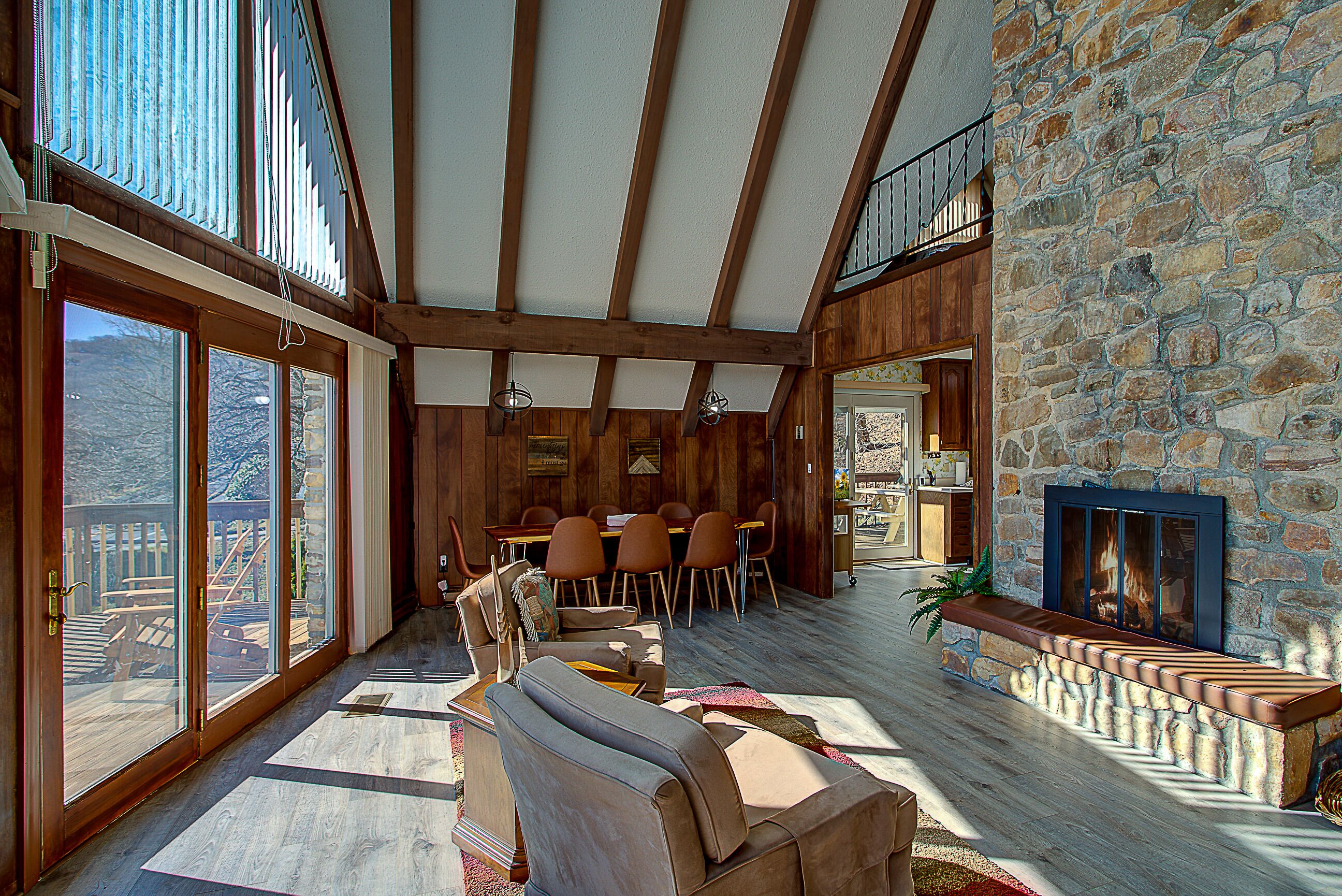 A spacious living area with a stone wall, wooden beams, and large windows.