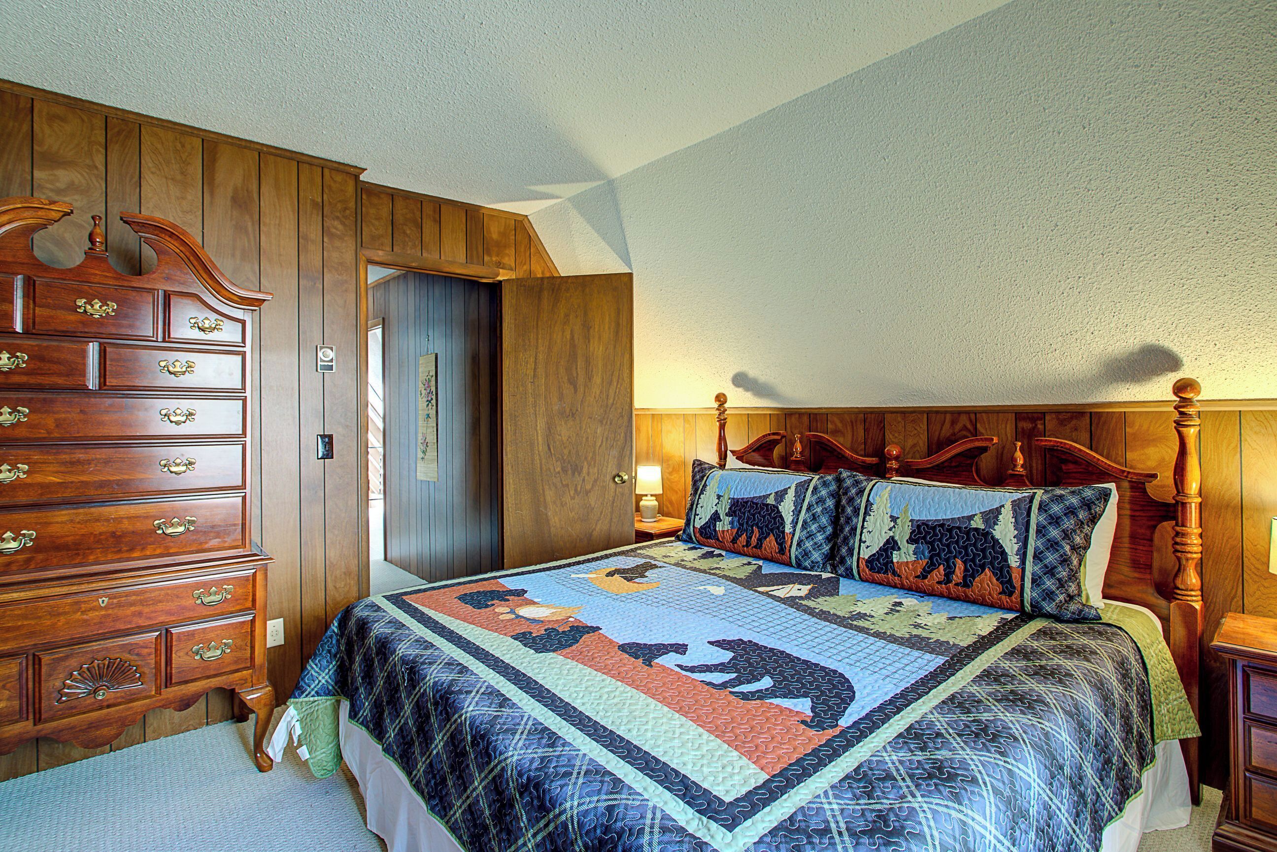Une chambre à coucher avec une commode en bois, une couvre-lit matelassé et une tête de lit en bois.
