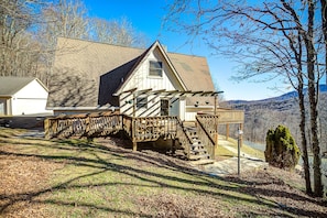 Situated on a sloped terrain, this house offers a view of the surrounding landscape and trees.