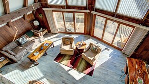 Un vaste espace de vie doté de planchers en bois, d’un ensemble de canapés, d’une table basse et d’une table à manger.