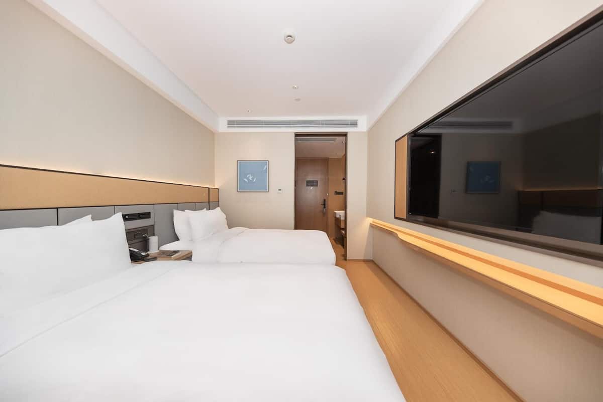 Una camera d'albergo con un letto grande, comodini, una televisione e una porta che dà su un bagno.