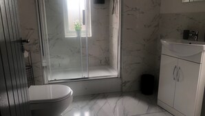 A bathroom with a toilet, a shower area, and a sink.