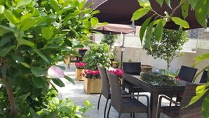 An outdoor patio area with wicker furniture, potted plants, and a pergola providing shade. - Fuda Fashion Hotel (Chongqing)