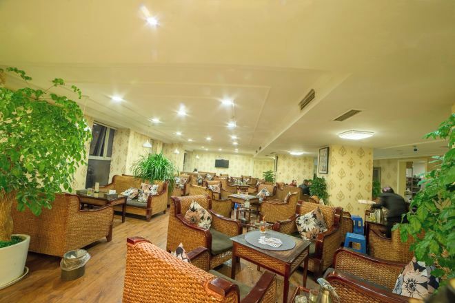 Un restaurante con mobiliario de mimbre, plantas en macetas y suelo de baldosas.