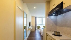 A narrow hallway leading to a bedroom with a large mirror, a sink, and a stove. - Fuda Fashion Hotel (Chongqing)